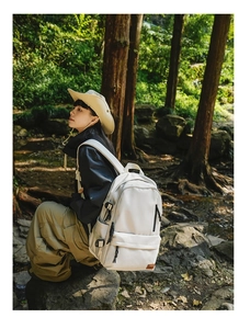 Detail of off-white large outdoor backpack with side buckles in forest camping setting