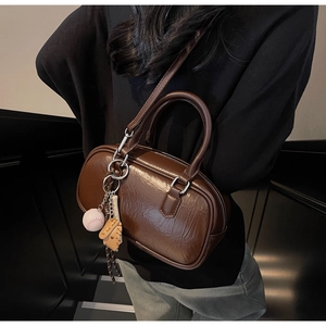 Détail du sac polochon en cuir marron froissé avec charm baseball et boucles argent