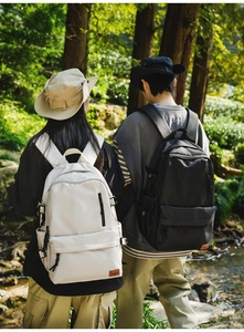 Detailed view of beige and black waterproof nylon backpacks in outdoor forest setting