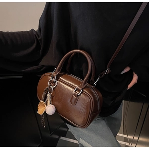 Détail d'un sac Boston en cuir marron foncé avec texture vintage et charmes de sport
