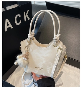 Detail view of white marble texture handbag with gold hardware and plush charm decoration