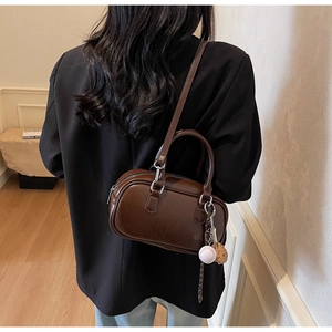 Détail du sac Boston marron foncé avec pendentif baseball et bandoulière réglable