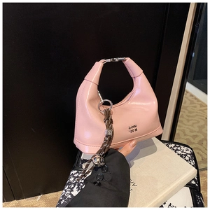 Detail of pink patent leather hobo bag with metal logo and woven handle decoration
