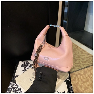 Detail of pink patent leather half-moon bag with silver handle and woven bell charm