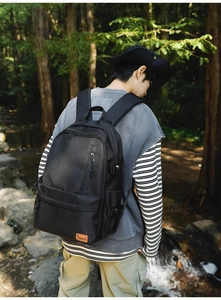 Outdoor shot of a black multipurpose backpack with vertical zipper and side buckle detail