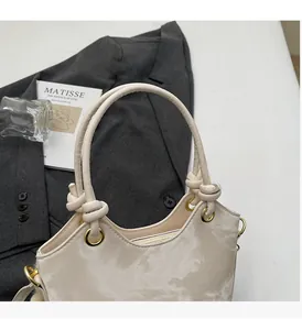 Detail of light beige bucket bag showing knotted handle and gold metal ring attachment