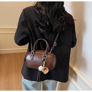 Vue détaillée du sac à main en cuir marron foncé avec un accessoire de sport suspendu