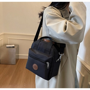 Detail of black nylon crossbody bag styled with a trench coat for a casual city look