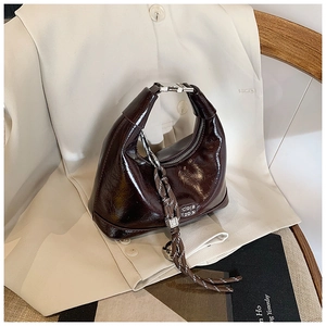 Close-up of vintage brown oily leather dumpling bag with silver buckle and braided charm