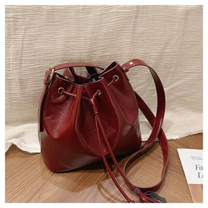 Détail du sac seau bordeaux avec cordon de serrage, gland et ferrures dorées