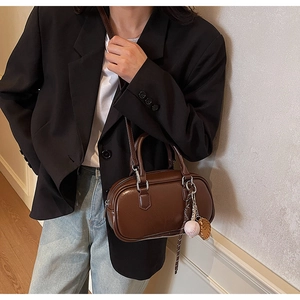 Détail du sac Boston marron poli avec charm de gant de baseball et bandoulière amovible