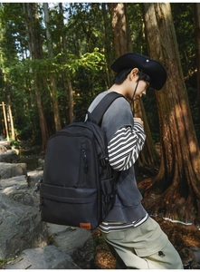 Close-up of black heavy-duty nylon backpack with leather logo in an outdoor setting