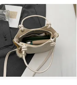 Top view of cream white bucket bag showing spacious interior with leather strap and pompom