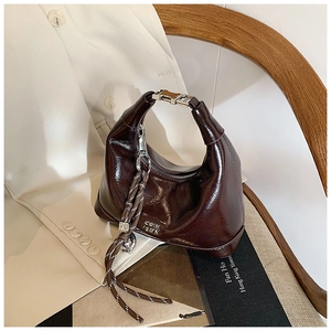 Close-up of a dark brown glossy leather dumpling bag with woven rope detail and metal buckle