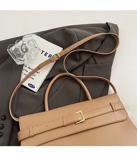 Detail of khaki leather briefcase with crossbody strap on a grey suit jacket