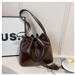 Détail d'un sac seau chocolat foncé avec fermeture à cordon et finition cuir brillant
