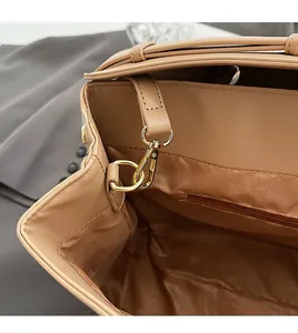Detail of khaki leather briefcase showing gold metal hooks and zipped fabric lining