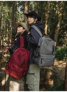 Outdoor multifunctional backpacks in deep red and grey shown on models in a forest setting