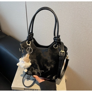 Detail of black marble textured bucket bag with knot handles and plush doll charm