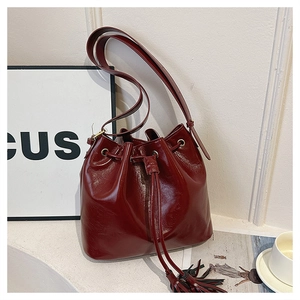 Détail macro du sac seau bordeaux avec fermeture à cordon et texture en cuir brillant