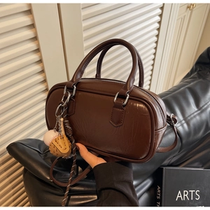Vue détaillée du sac Boston marron montrant le cuir texturé et le pendentif de baseball