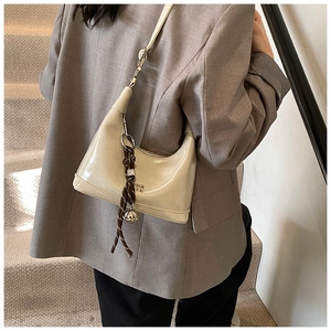 Chic cream patent leather hobo bag styled with a minimalist grey suit on a staircase