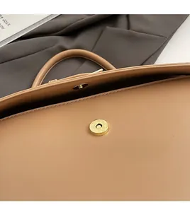 Close-up of golden magnetic clasp on light brown leather bag with elegant grain