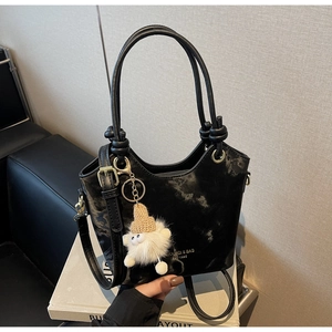 Detail of black marble textured tote with knot handle and plush doll charm
