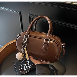 Détail du sac à bandoulière vintage marron avec texture plissée et breloque baseball