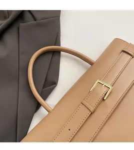 Close-up of camel leather briefcase handle with metal buckle and premium stitching detail