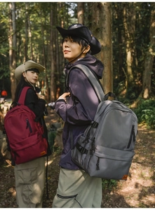 Outdoor backpacks in dark grey and red shown in a forest setting with dual models