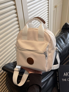 Minimalist beige nylon crossbody bag with brown leather handles and adjustable straps