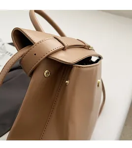 Detail view of premium brown leather briefcase with high-quality gold hardware and fine stitching