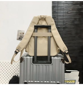 Sac à dos beige avec sangle de bagage fixée sur la poignée d'une valise argentée