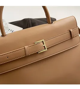 Close-up of caramel leather handbag featuring fine stitching and light gold metal buckle