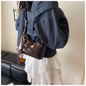 Detail of vintage brown leather hobo bag with white lettering and woven tassel detail