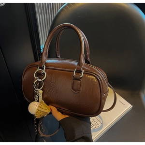Détail du sac polochon vintage en cuir marron avec pendentif baseball et sangle