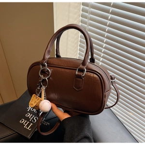 Détail d'un sac Boston en cuir plissé marron avec un pendentif de baseball vintage au manche