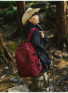 Detail view of burgundy outdoor backpack with side buckles and brand leather logo