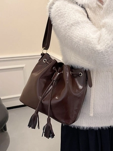 Sac seau vintage en cuir marron avec fermeture à cordon et pompons élégants