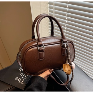 Détail du sac Boston marron rétro avec pendentif baseball et poignées cylindriques