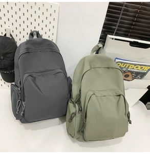 Vue détaillée de sacs à dos en nylon imperméable gris et vert avec poches latérales utiles