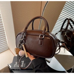 Détail du sac Boston en cuir marron foncé avec breloques baseball et pièces argentées