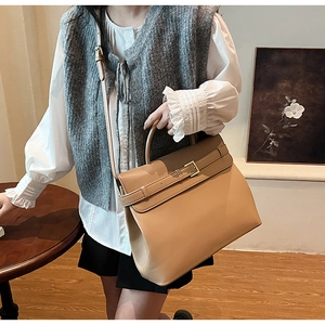 Close-up of khaki leather briefcase with crossbody strap and decorative buckle detail
