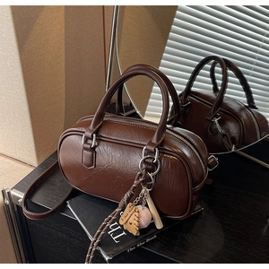 Détail du sac cylindre marron vintage avec cuir plissé et breloque de baseball