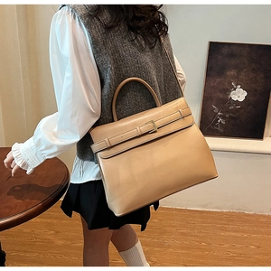 Beige matte leather tote bag styled as a crossbody in a cozy, minimalist setting