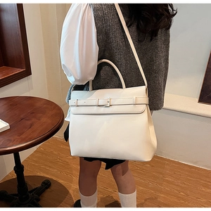 Detail view of large white leather briefcase showing buckle strap and adjustable shoulder strap