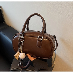 Détail du sac Boston marron foncé avec texture vintage et pendentif gant de baseball
