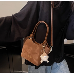 Sac seau en daim marron avec anse tressée, logo doré et pendentif en peluche mignon