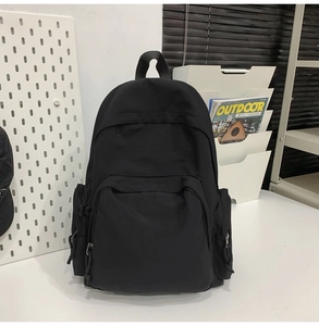 Détail d'un sac à dos noir minimaliste montrant fermetures et poches latérales
